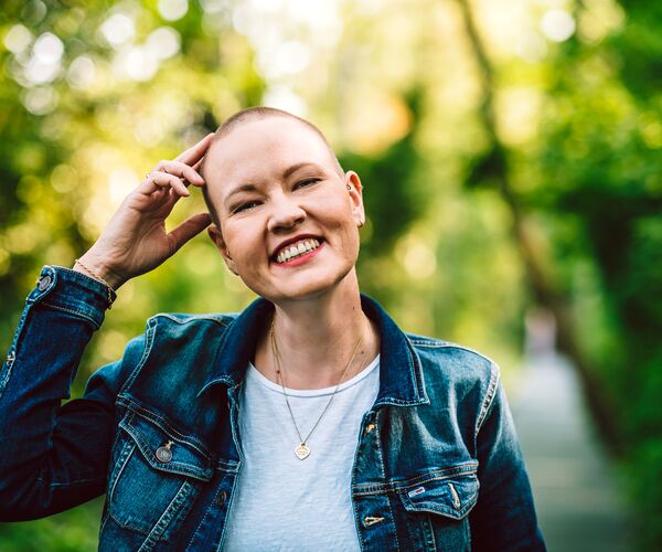 Portrait von Laura, die lachend eine Hand am Kopf hat